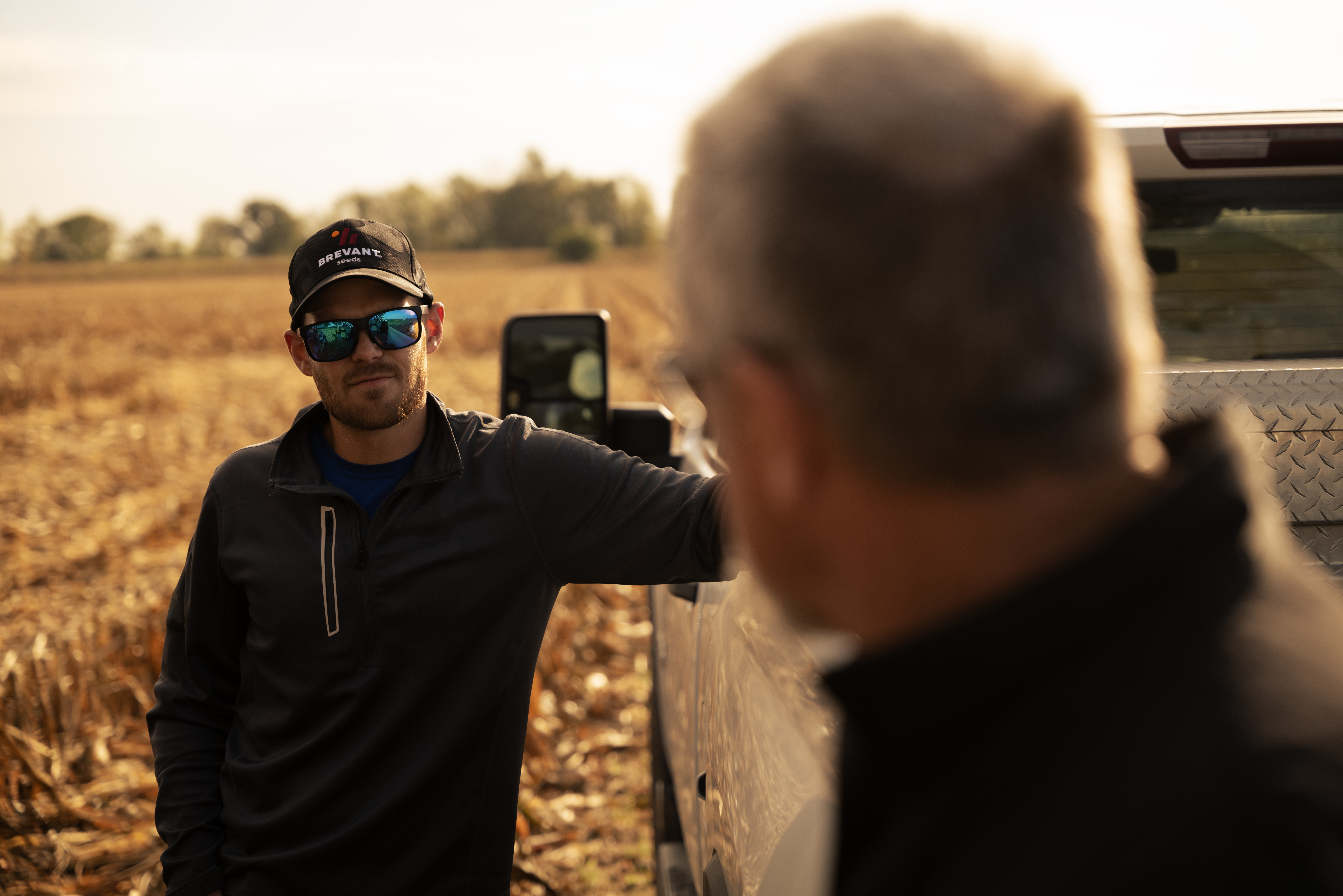 Man in a bBrevant Seeds hat standing next to a truck